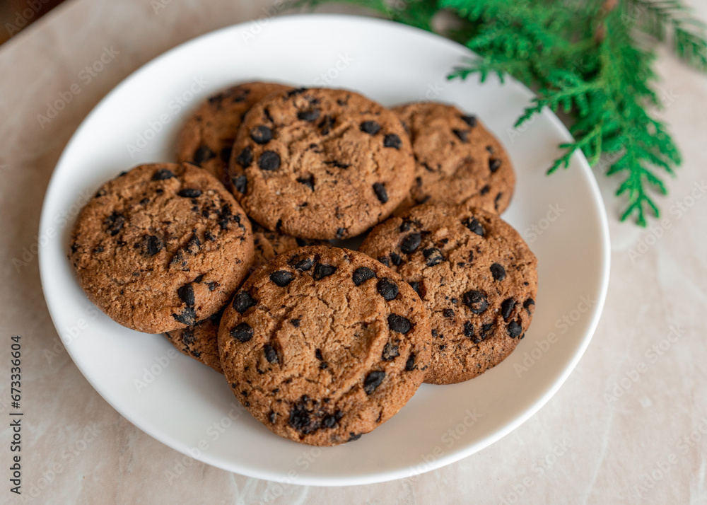 Chocolate cookies on a plate with spruce branches on the table. Dark chocolate cookies on a plate, Christmas cookies chocolate cinnamon sweet dessert holiday treat new year and christmas food