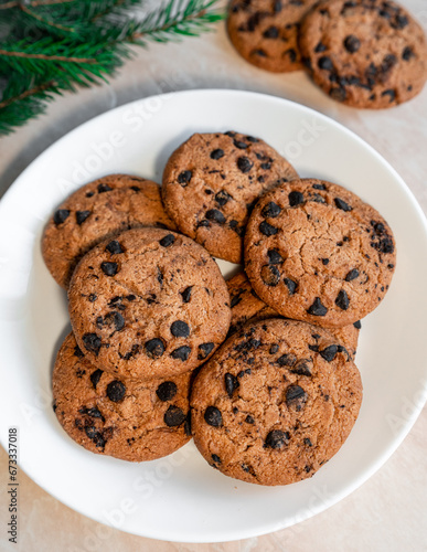 Chocolate cookies on a plate with spruce branches on the table. Dark chocolate cookies on a plate, Christmas cookies chocolate cinnamon sweet dessert holiday treat new year and christmas food