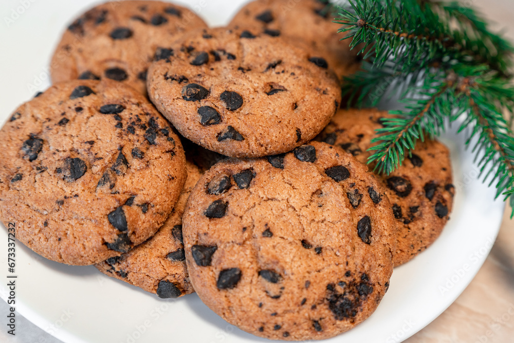 Chocolate cookies on a plate with spruce branches on the table. Dark chocolate cookies on a plate, Christmas cookies chocolate cinnamon sweet dessert holiday treat new year and christmas food Chocolate cookies on a plate with spruce branches on the table. Dark chocolate cookies on a plate, Christmas cookies chocolate cinnamon sweet dessert holiday treat new year and christmas food