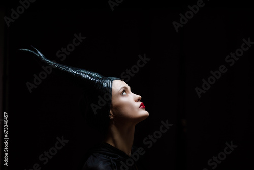 beautiful woman with plump lips witch fairy in black clothes and with horns, devil costume with horns. photo