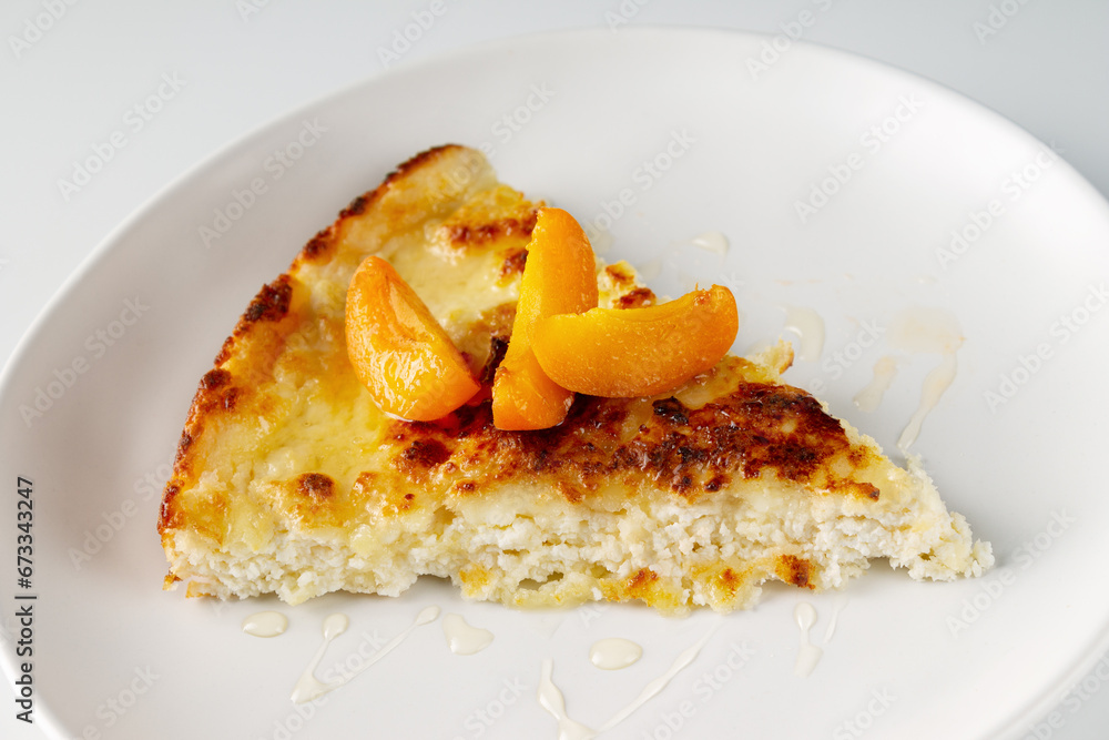 triangular piece of cheesecake with honey and apricots on a white plate
