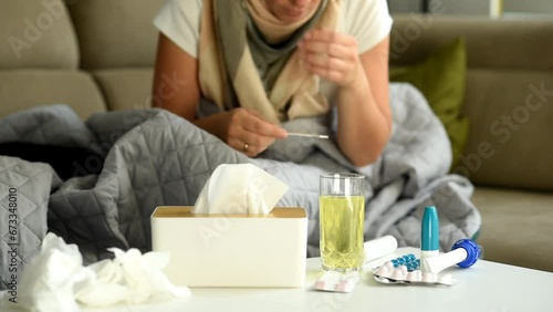 Wallpaper Mural Medicines and medical supplies are laid out on the table. The woman measures the temperature with a mercury thermometer, checks the value on the thermometer and puts it on the table. Illness and poor  Torontodigital.ca