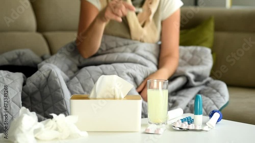 Medicines and medical supplies are laid out on the table. The woman takes a mercury thermometer and puts it under her arm to measure the temperature. Illness and poor health at home