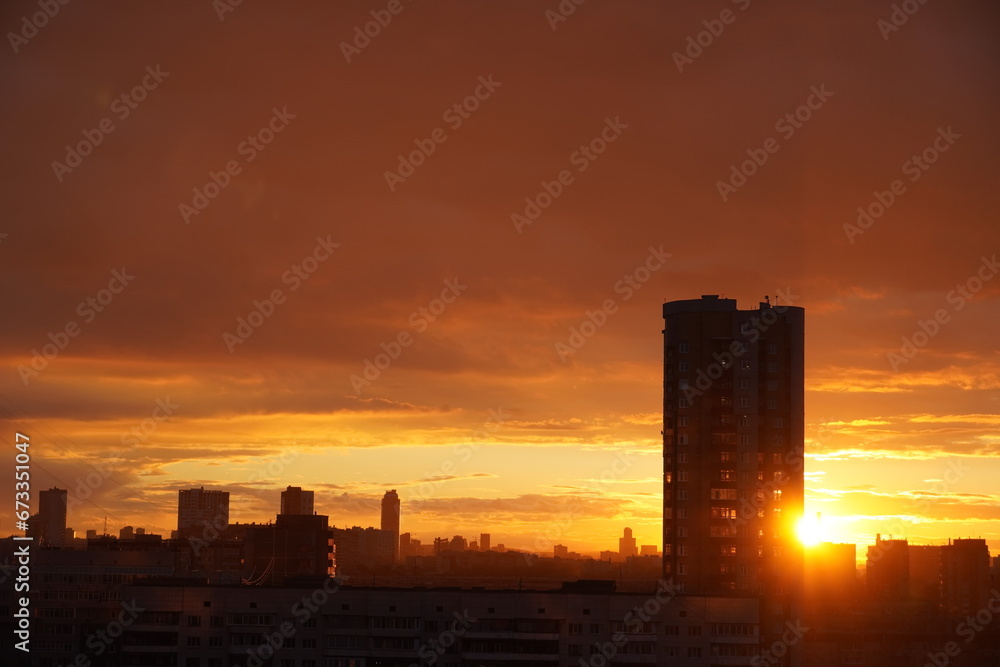 Beautiful cityscape with orange sky in yellow-gray tones of the setting sun passing through the corner of a high-rise building