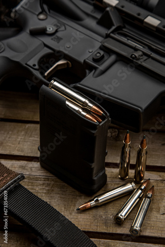 Close-up of .223 carbine cartridges. Loaded weapon clip. Weapons in the back