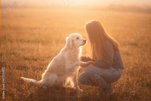 golden retriever dog and a young woman sharing a moment at sunset doing the paw trick photo