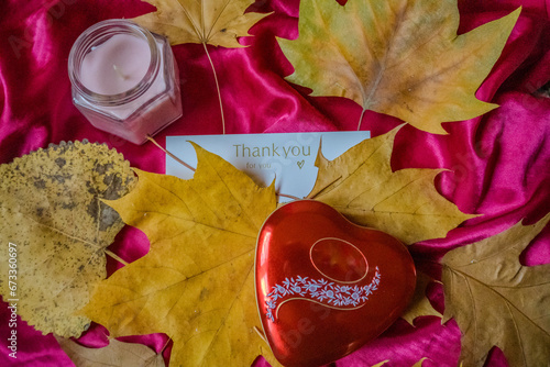 Present of Valentine on pink silk. Red heart with candle surrounded by leaves 