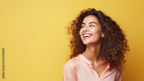 Portrait of a cheerful young woman wearing yellow shirt standing isolated over yellow background