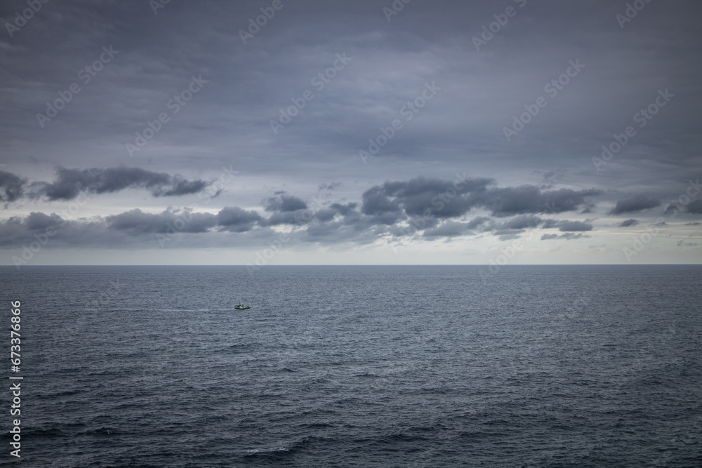 Small fishing boat sailing in the vastness of the sea
