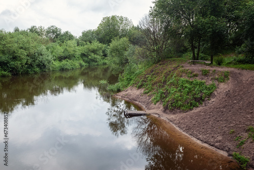 Landscape of the Bend of the Minija River in Lithuania, Natural view of nature, beautiful river bank, old wooden bathing bridge and a bench for resting in the shade photo