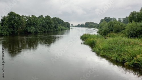 Light summer rain and its drops falling into the river water. Calm landscape of Lithuania