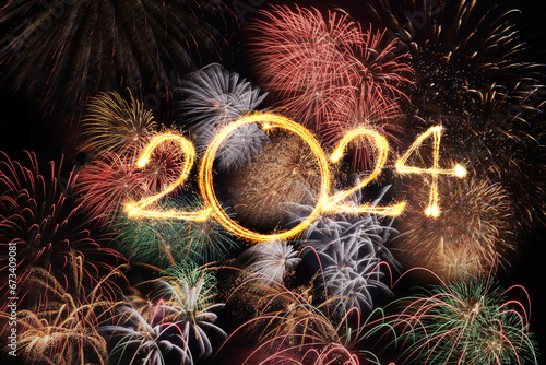 Happy new year 2024 text written with Sparkle fireworks in celebration with fireworks spakling on night sky background
