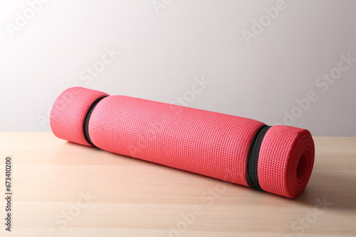 red mat folded into a roll, karemat for camping or yoga, on a table 