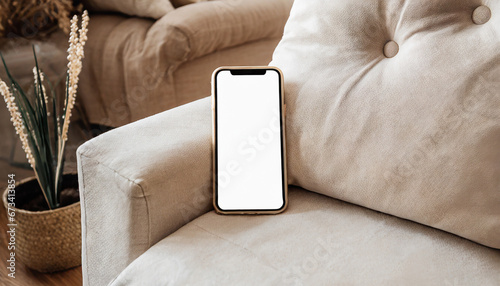 Phone with blank screen lying on the light couch or chair. Smart phone mock-up in neutral tones