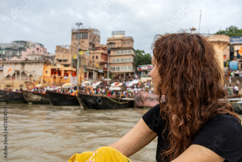 Woman looks the view of the Ganges with its boats, people and sacred water of Varanasi in India photo