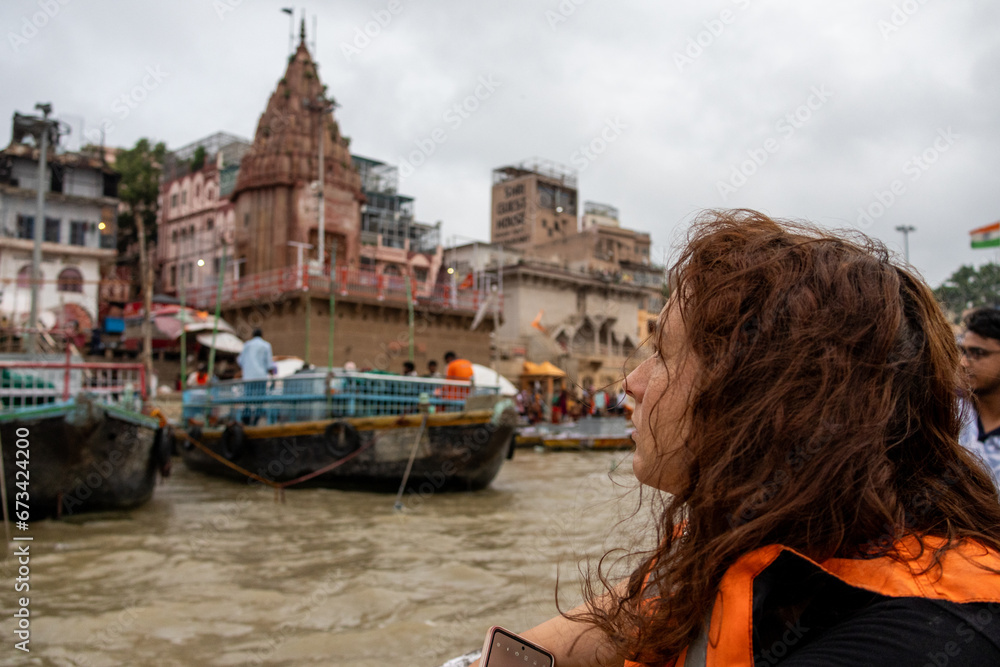 Woman looks the view of the river Ganges with its boats, people and sacred water of Varanasi in India
