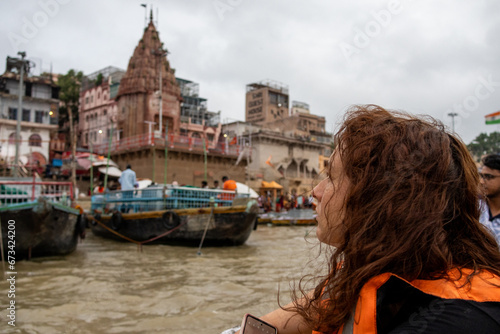Woman looks the view of the river Ganges with its boats, people and sacred water of Varanasi in India