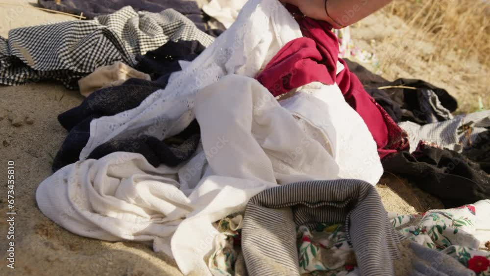 Hand searching through used desert clothes of textile dump, fast fashion concept Hand searching through used desert clothes of textile dump, fast fashion concept