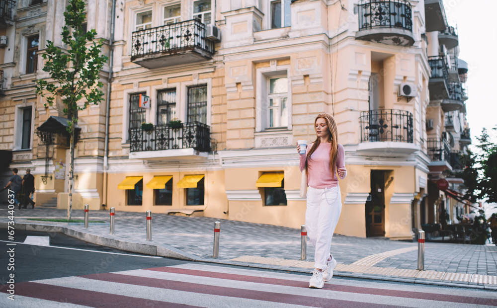 Cheerful woman crossing road with coffee cup
