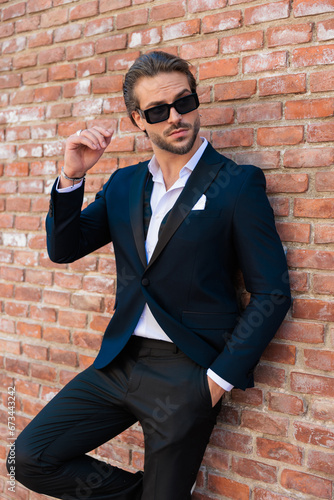 sexy elegant man with sunglasses holding hand in pocket and looking to side
