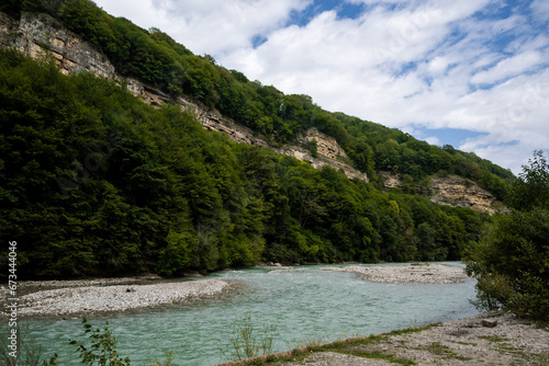 Mountain river in the mountains, green forest nearby, blue sky