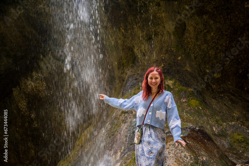 Happy ginger girl in blue dress and jacket enjoying the waterfalls  smiling