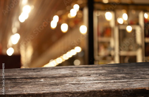 Wooden table top on blurred cafe showcase with light bulb. Background for product display montage or key visual design  abstraction