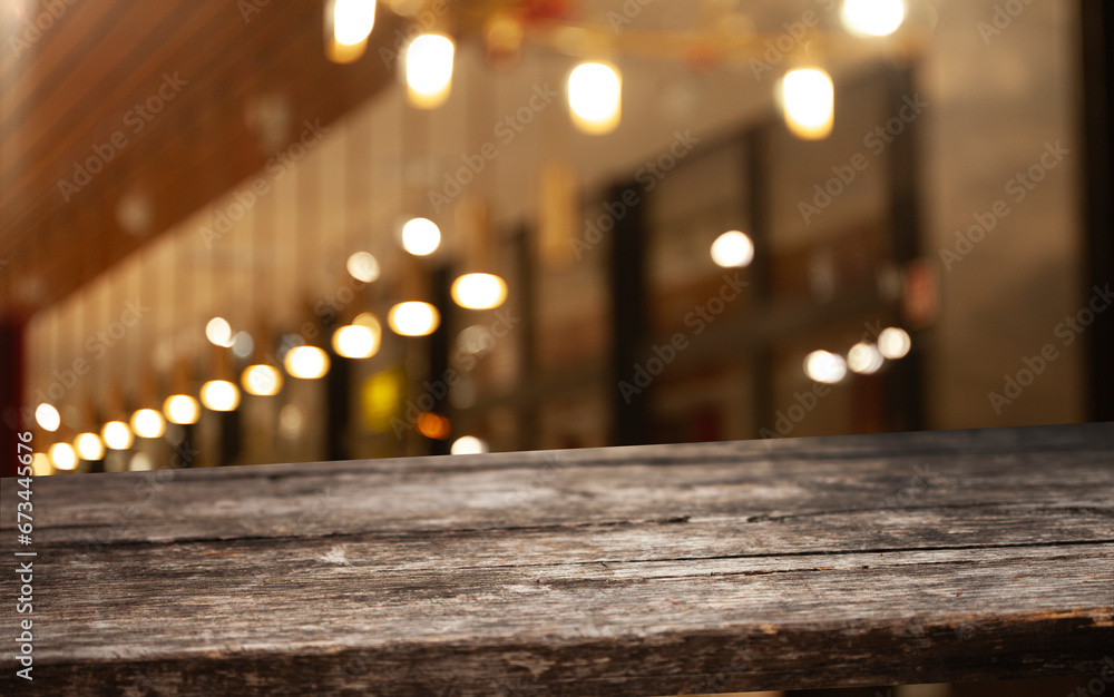 Wooden table top on blurred cafe showcase with light bulb. Background for product display montage or key visual design, abstraction