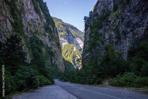 A rocky gorge in Abkhazia with steep walls and a narrow road between them on a sunny summer day
