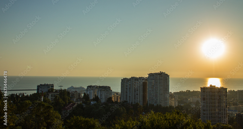 Panoramic view of the city of Sochi with modern residential buildings and apartments on the background of sunset and the horizon line over the sea and a space for copying