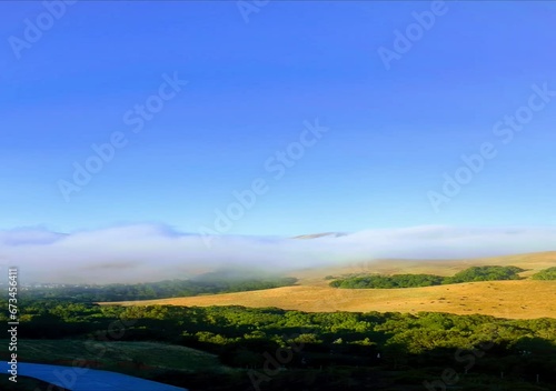 foggy morning landscape with rolling hills and blue sky