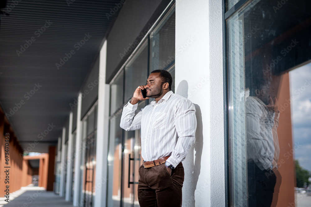 A man leaning against a building talking on a cell phone. A Man Engaged in a Phone Conversation Outside a Urban Structure A man leaning against a building talking on a cell phone. A Man Engaged in a Phone Conversation Outside a Urban Structure