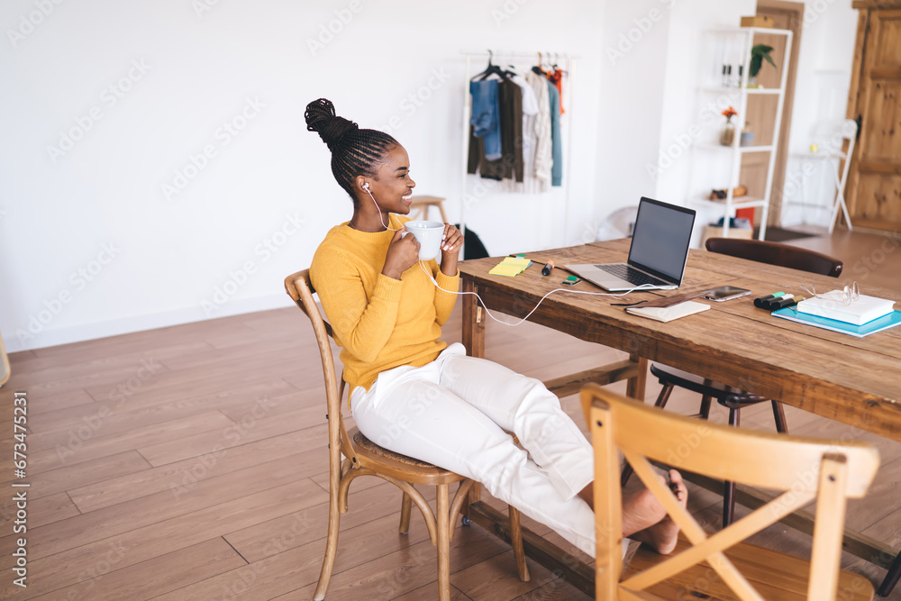 Black woman drinking coffee at table with laptop Black woman drinking coffee at table with laptop