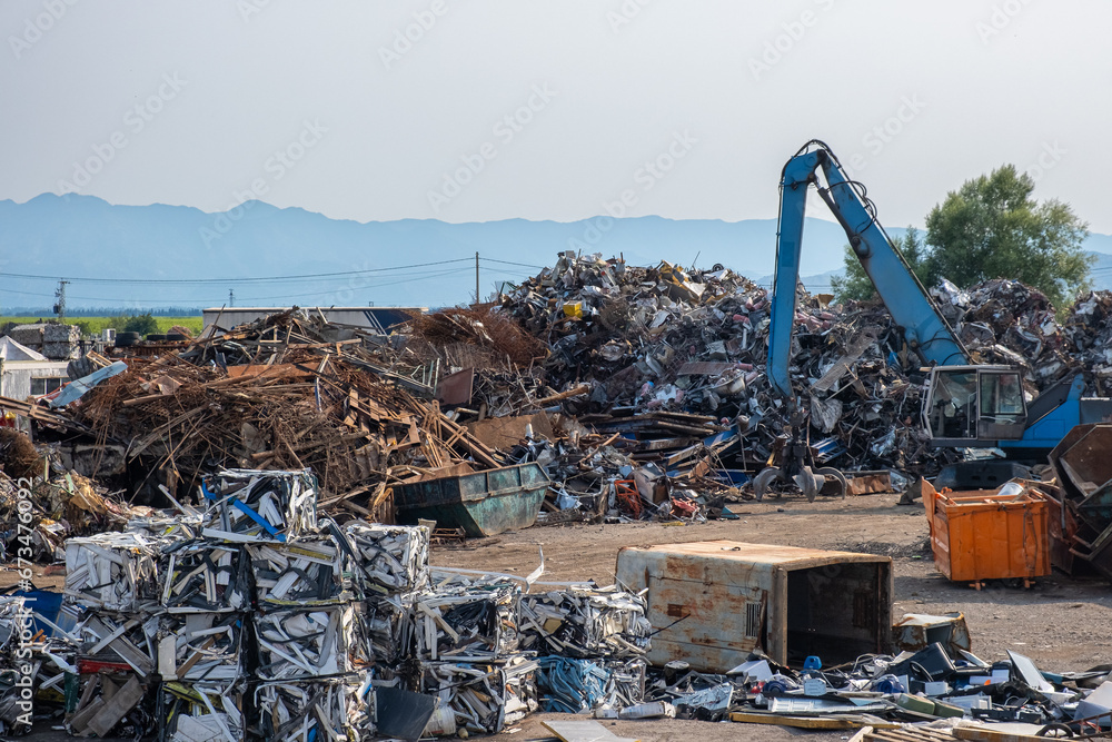 Industrial scrap metal recycling in junkyard. Clow crane picking up metal, aluminum, brass, copper, stainless steel. Recycling industry. Environment and zero waste concept - obrazy, fototapety, plakaty 