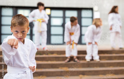 Little boy make karate exercises on the city street