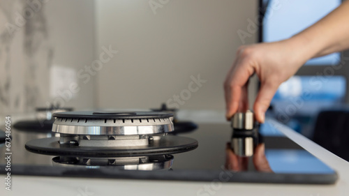 A woman's hand lights a gas stove in the kitchen. Turn gas on or off. The concept of gasification in the house.
