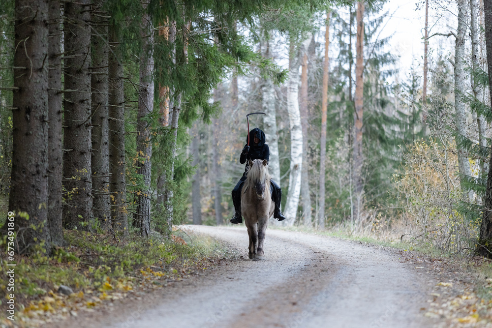 Reaper riding on gravel road in Autumn scenery. Ghost rider. Icelandic horse. Halloween.