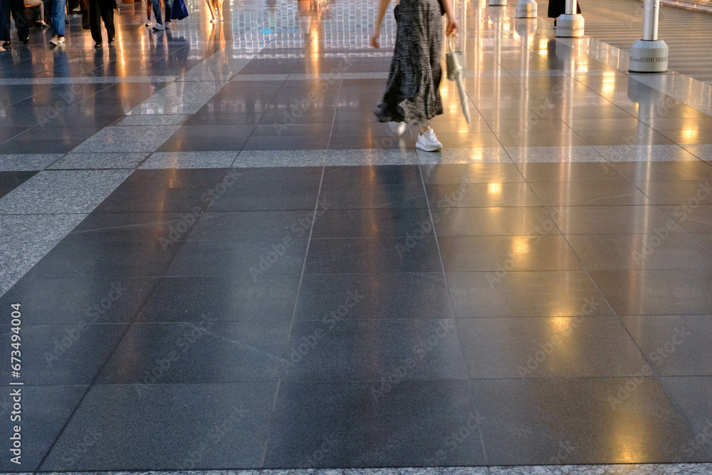 光を反射してキラキラ光る道を歩く人。jr大阪駅構内で撮影