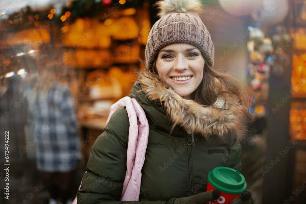 happy woman in green coat and brown hat at winter fair in city happy woman in green coat and brown hat at winter fair in city