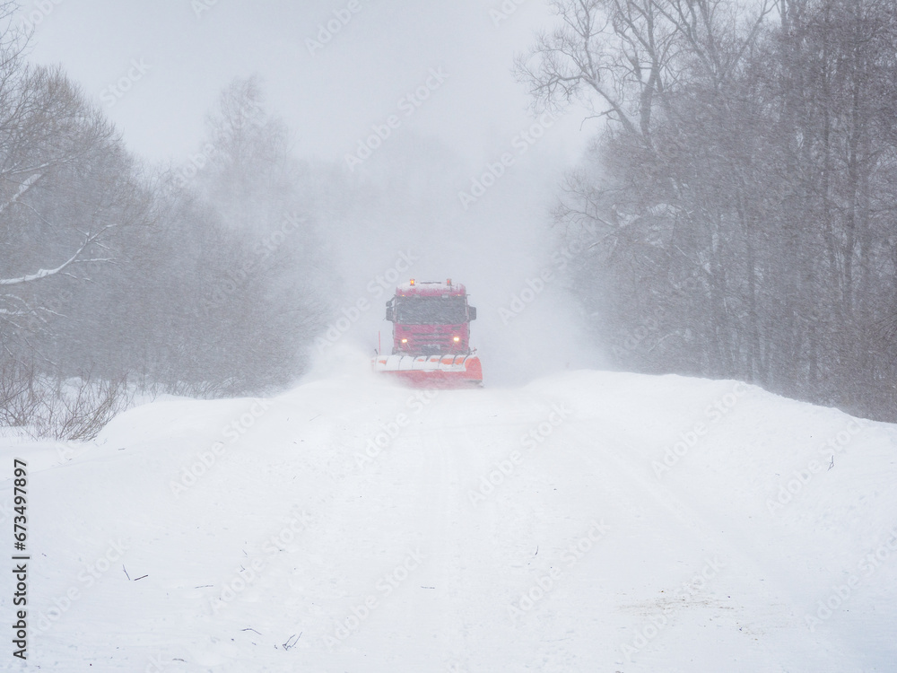 A snowplow clears a snow-covered road. A snowplow clears a snow-covered road.