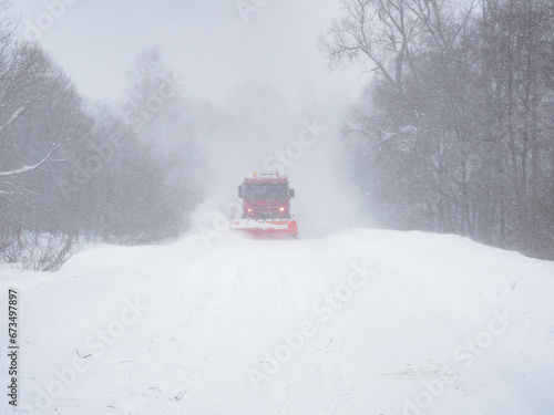 A snowplow clears a snow-covered road.