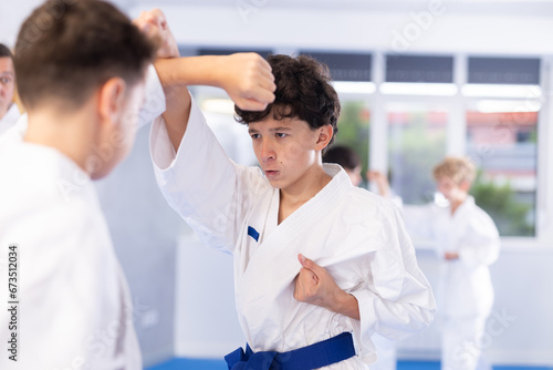 Diligent preteen karate students practicing fighting techniques during workout session