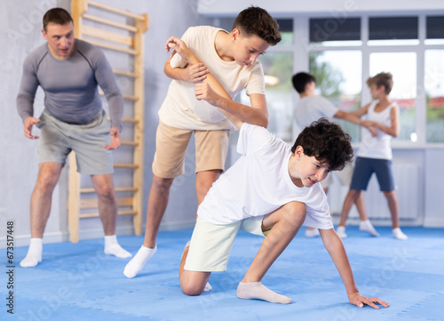 Sedulous underage practitioner of self-defense courses applying arm twist on his opponent in standing position