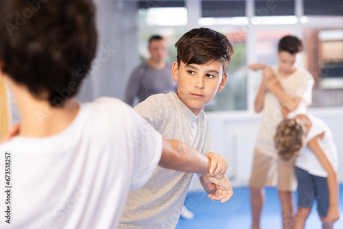 Diligent preteen student practicing self-defense techniques in pairs during workout session