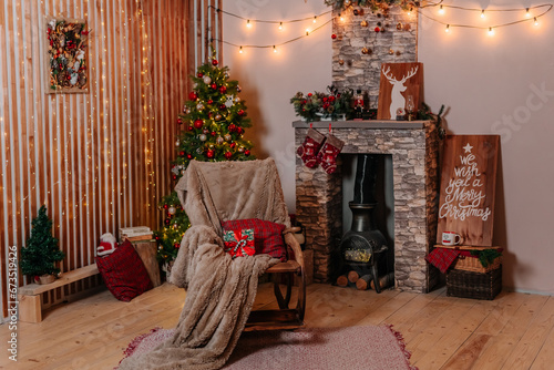 Beautiful Christmas decorations. A photostudio new year home interior: Christmas tree with red Christmas Baubles, rocking chair and stockings above the fireplace. Country style home decor. 