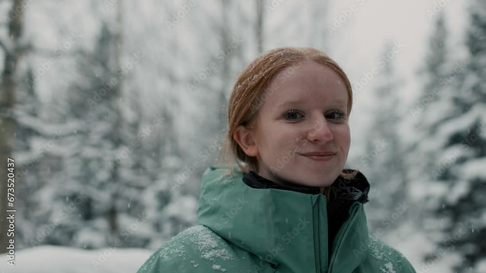 female hiker stops, looks around, and smiles to camera as snow falls in the mountains around her female hiker stops, looks around, and smiles to camera as snow falls in the mountains around her