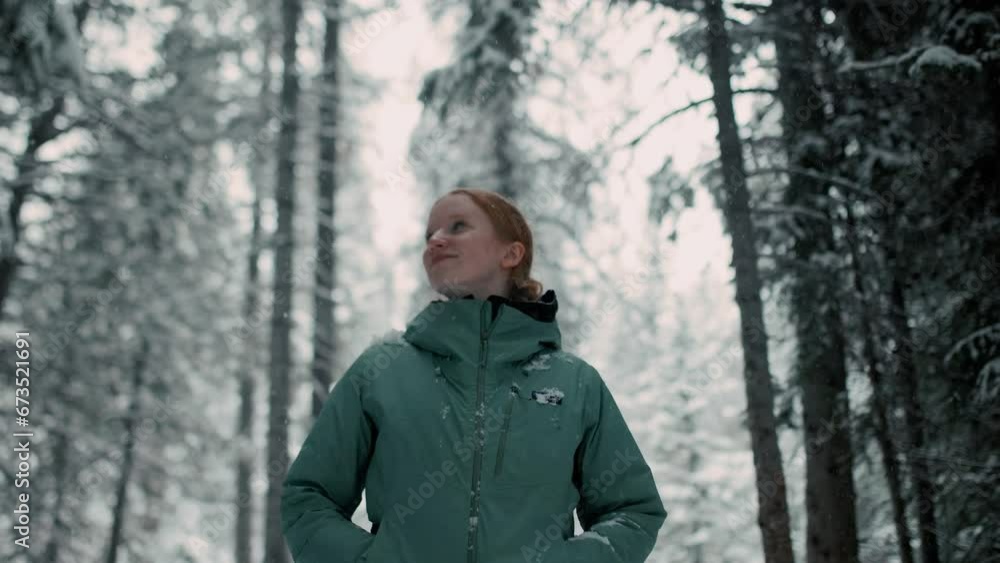 female hiker stops, looks around, and smiles to camera as snow falls in the mountains around her female hiker stops, looks around, and smiles to camera as snow falls in the mountains around her