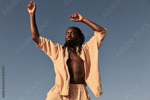 Black man dancing against blue sky