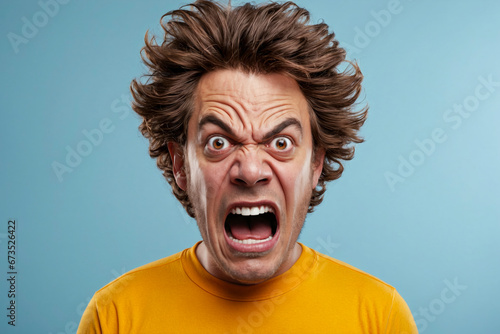 A man with wild, disheveled hair and an exaggerated angry expression against a blue background. photo