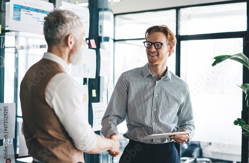 Cheerful colleagues shaking hands after successful business project